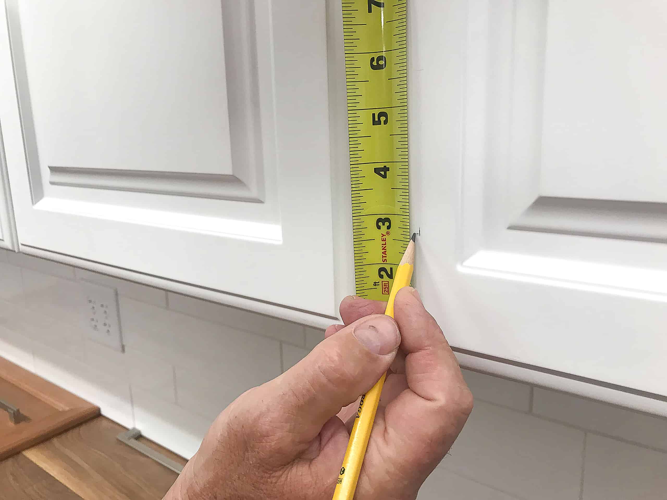Tape measure marking white kitchen cabinet door