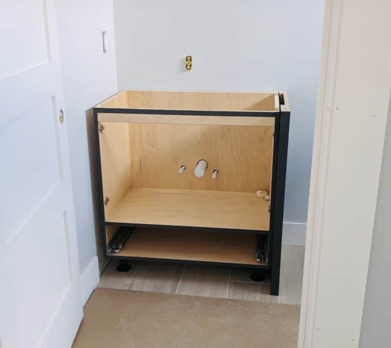 Installing cabinetry over bathroom sink plumbing.